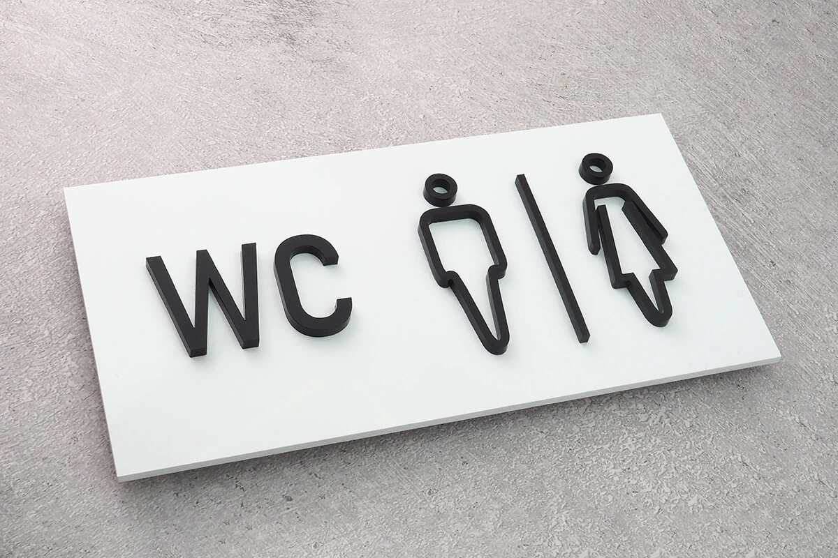 Biała tabliczka WC z czarnymi symbolami męskim i damskim
