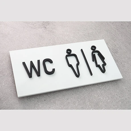 Biała tabliczka WC z czarnymi symbolami męskim i damskim
